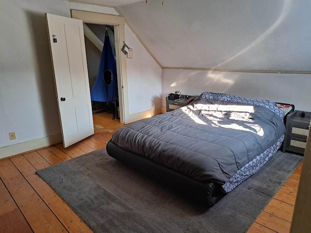 bedroom with baseboards, hardwood / wood-style flooring, and lofted ceiling