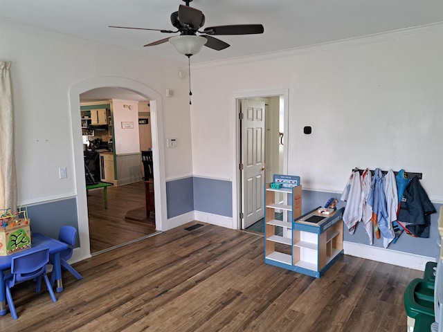 playroom featuring arched walkways, wood finished floors, crown molding, and a ceiling fan