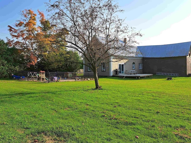 view of yard featuring fence, a deck, and a playground
