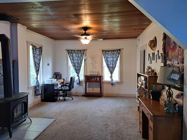 carpeted office space featuring a wood stove, wood ceiling, a ceiling fan, and crown molding