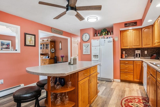 kitchen featuring tasteful backsplash, white appliances, ceiling fan, light hardwood / wood-style flooring, and a baseboard heating unit