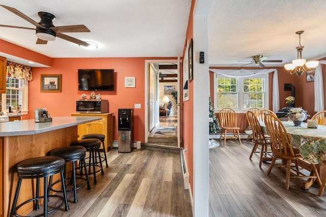 kitchen with a textured ceiling, a kitchen bar, dark wood-type flooring, and ceiling fan