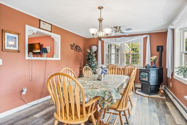 dining area featuring wood-type flooring, a baseboard radiator, crown molding, and a wood stove