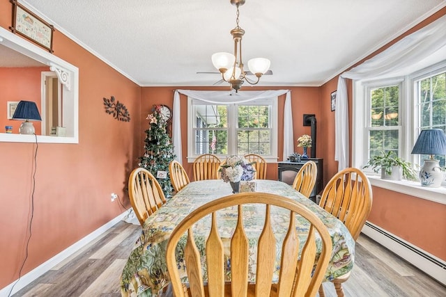 dining area with baseboard heating, crown molding, light hardwood / wood-style floors, and a wealth of natural light