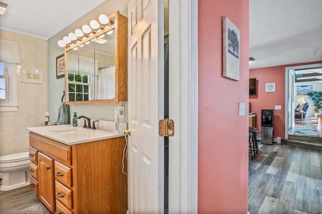 bathroom with a wealth of natural light, vanity, toilet, and hardwood / wood-style flooring