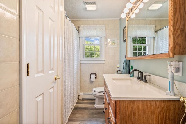 bathroom with vanity, toilet, ornamental molding, hardwood / wood-style floors, and a baseboard heating unit