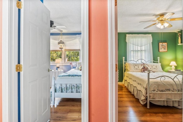 bedroom with a textured ceiling, wood-type flooring, and ceiling fan