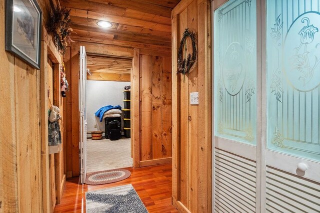 corridor with wood ceiling, wooden walls, and hardwood / wood-style floors