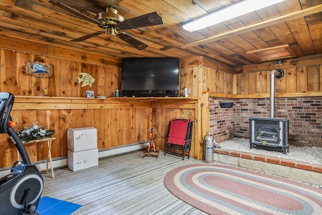 interior space with baseboard heating, wood walls, a wood stove, and wooden ceiling