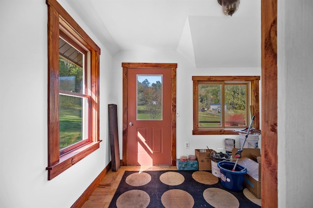 entryway with light wood-type flooring, lofted ceiling, and a healthy amount of sunlight