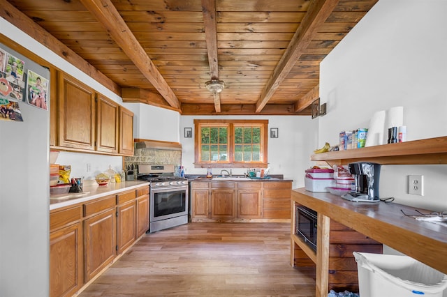 kitchen featuring wood ceiling, beam ceiling, stainless steel gas stove, light hardwood / wood-style flooring, and exhaust hood