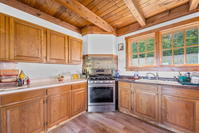 kitchen with decorative backsplash, stainless steel range with gas cooktop, wooden ceiling, beam ceiling, and light hardwood / wood-style flooring