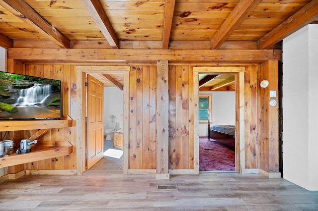 interior space featuring beamed ceiling, light wood-type flooring, wood walls, and wooden ceiling