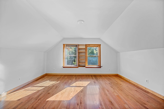 additional living space featuring light wood-type flooring and vaulted ceiling