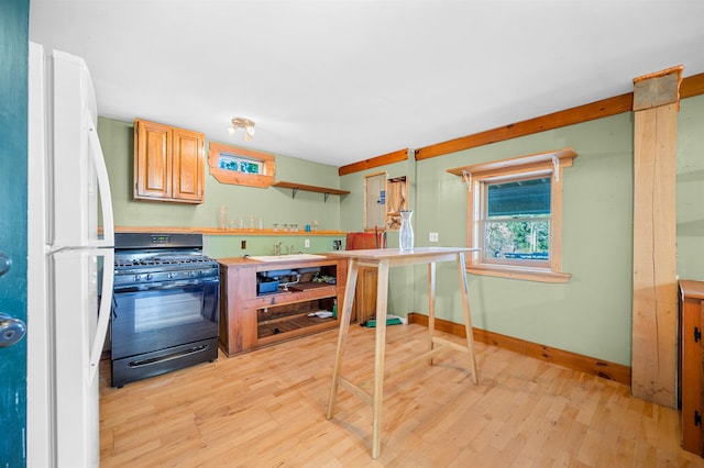 kitchen with white refrigerator, light hardwood / wood-style flooring, sink, and black gas range oven