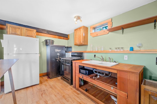 kitchen featuring light hardwood / wood-style floors, sink, black gas stove, and white fridge