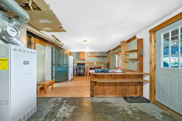 kitchen featuring concrete flooring, black gas stove, and white fridge