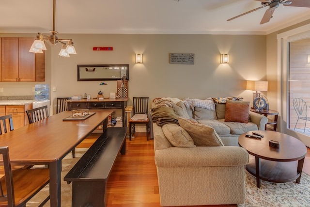 living room with ornamental molding, light wood-type flooring, ceiling fan, and a healthy amount of sunlight