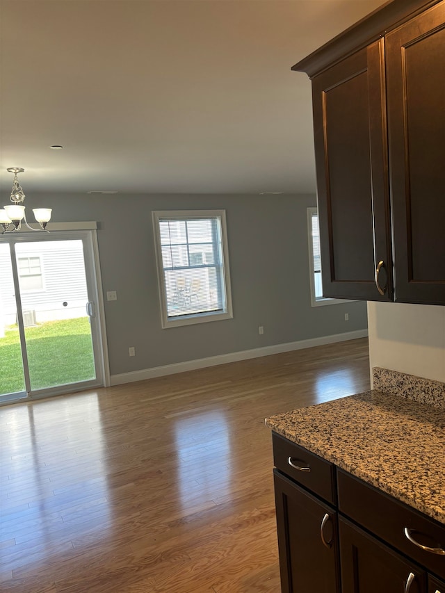 kitchen with light stone counters, light wood-type flooring, and an inviting chandelier