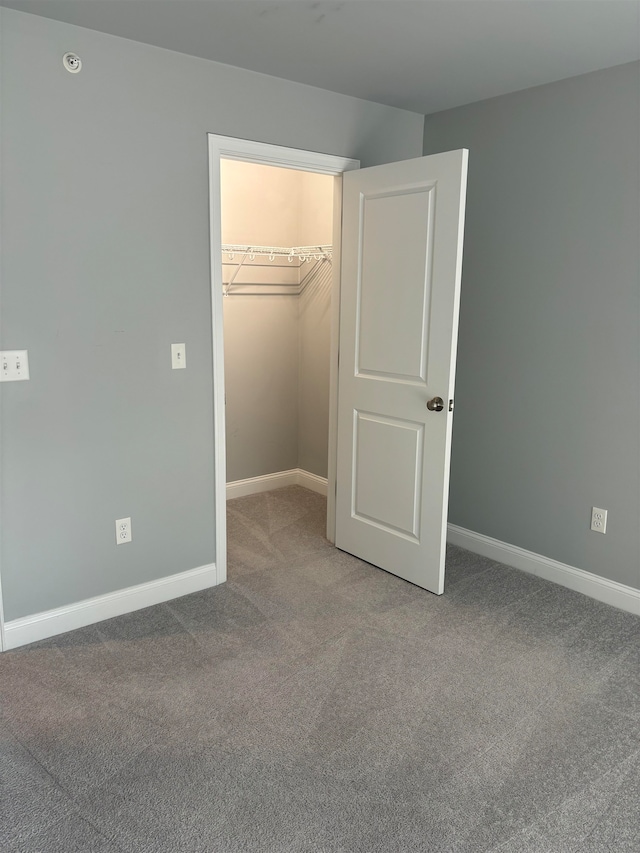 unfurnished bedroom with a walk in closet, carpet floors, and a closet