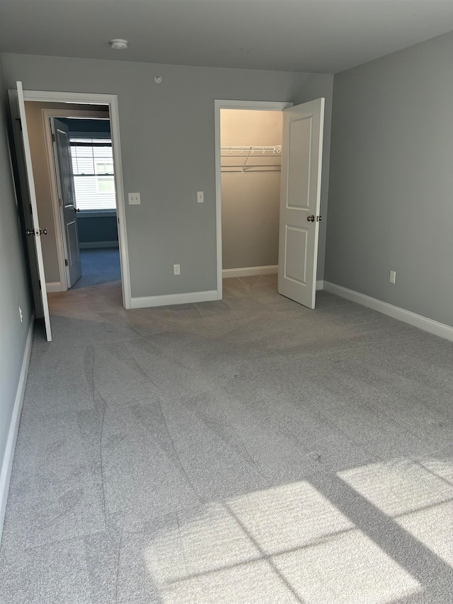 unfurnished bedroom featuring a walk in closet, a closet, and carpet floors