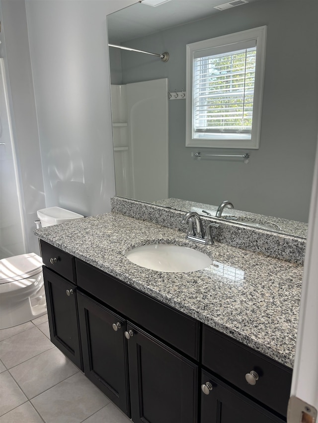 bathroom featuring toilet, vanity, tile patterned floors, and walk in shower