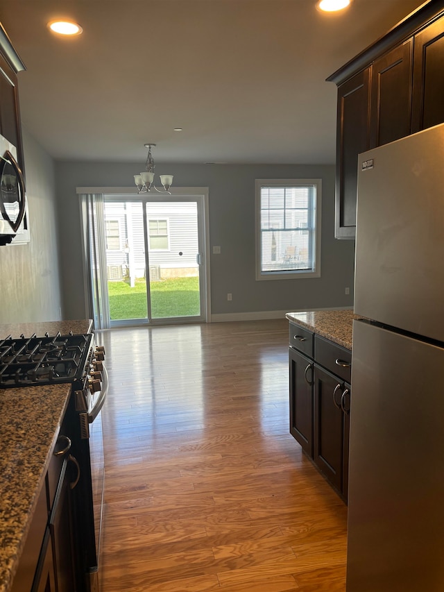 kitchen with stainless steel appliances, light hardwood / wood-style flooring, and dark stone countertops