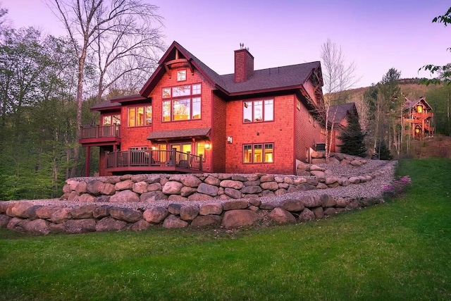 back house at dusk with a deck and a yard