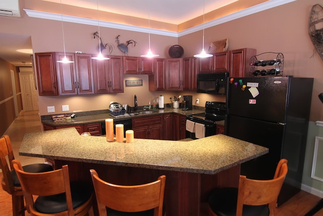 kitchen featuring a raised ceiling, a breakfast bar area, pendant lighting, black appliances, and sink