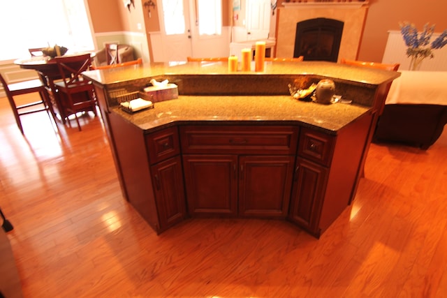 kitchen with light wood-type flooring, light stone counters, and a center island