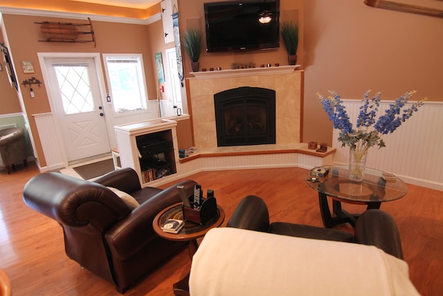 living room featuring light hardwood / wood-style floors, a tile fireplace, and crown molding