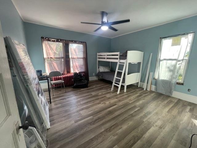 bedroom featuring multiple windows, crown molding, dark hardwood / wood-style flooring, and ceiling fan