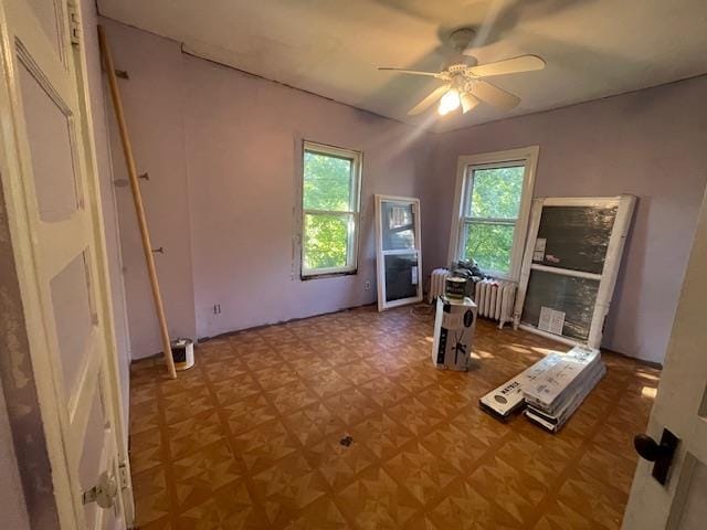 exercise area featuring ceiling fan, radiator, and plenty of natural light