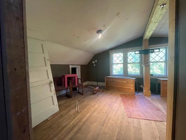 additional living space featuring vaulted ceiling with beams and hardwood / wood-style flooring