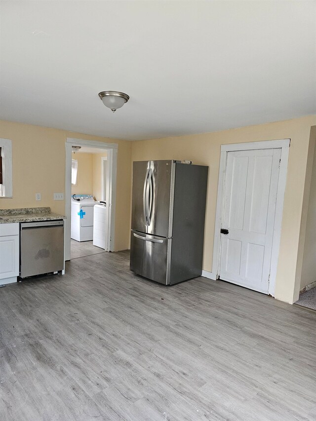 kitchen with light stone counters, white cabinets, light hardwood / wood-style flooring, stainless steel appliances, and separate washer and dryer