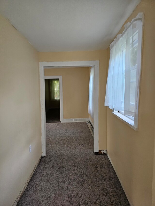 hallway with dark colored carpet and a baseboard radiator