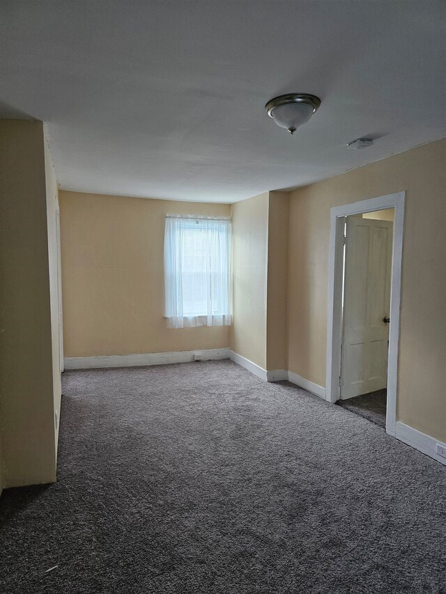 unfurnished room with dark colored carpet