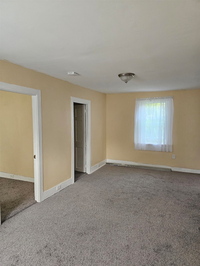 carpeted empty room featuring baseboard heating