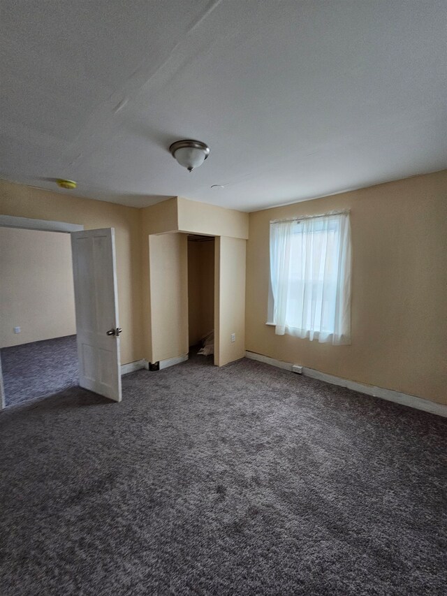 unfurnished room with dark carpet and a textured ceiling