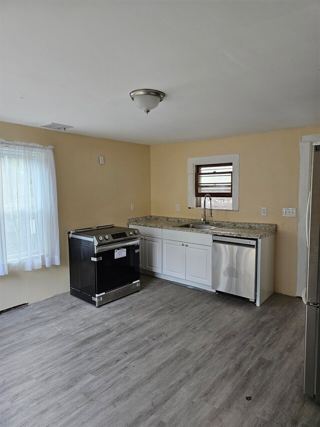 kitchen with hardwood / wood-style floors, white cabinetry, sink, and stainless steel appliances