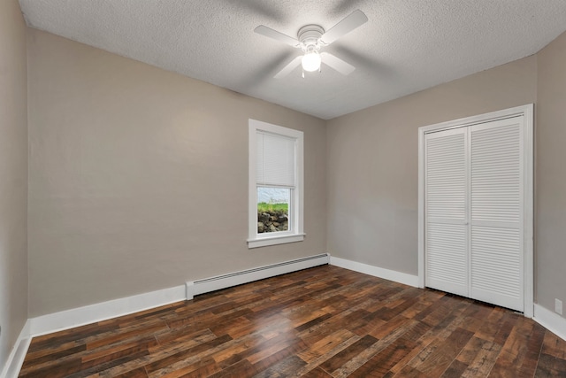 unfurnished bedroom featuring ceiling fan, a textured ceiling, dark hardwood / wood-style floors, and a baseboard heating unit