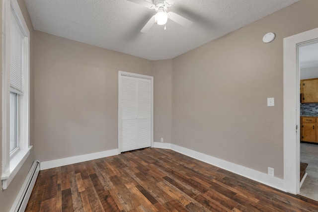 empty room with a textured ceiling, ceiling fan, a baseboard heating unit, and dark hardwood / wood-style flooring