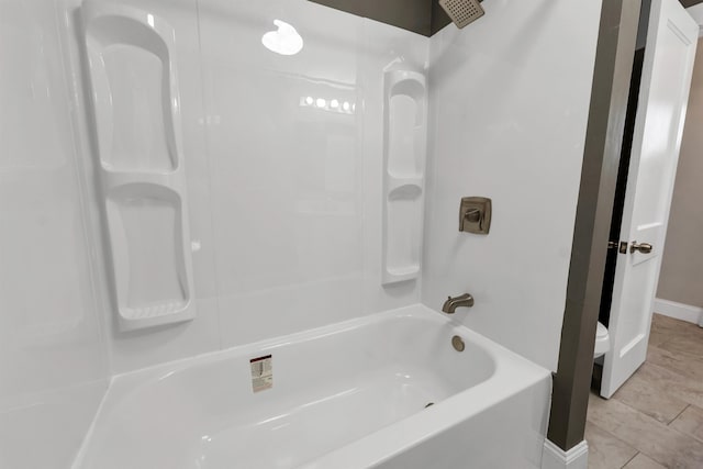 bathroom featuring toilet, shower / washtub combination, and tile patterned floors