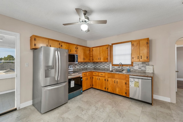 kitchen featuring appliances with stainless steel finishes, a healthy amount of sunlight, sink, and ceiling fan