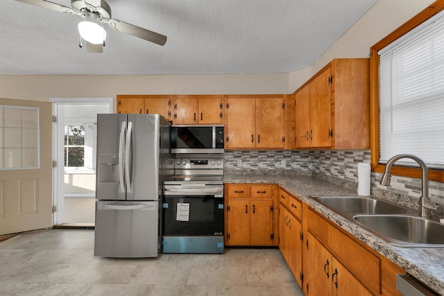 kitchen featuring a textured ceiling, sink, decorative backsplash, stainless steel appliances, and ceiling fan