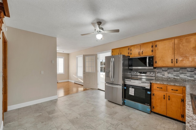 kitchen with a textured ceiling, a baseboard radiator, stainless steel appliances, decorative backsplash, and ceiling fan