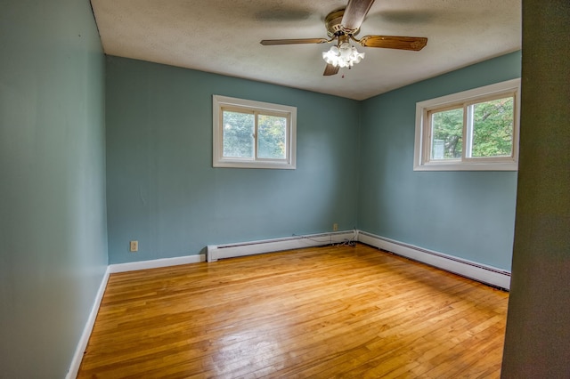 empty room featuring hardwood / wood-style flooring, a baseboard heating unit, a textured ceiling, baseboards, and ceiling fan