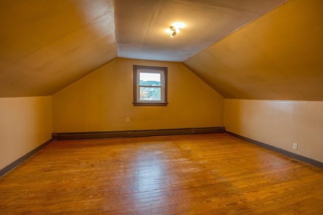 bonus room with a baseboard heating unit, baseboards, wood finished floors, and vaulted ceiling