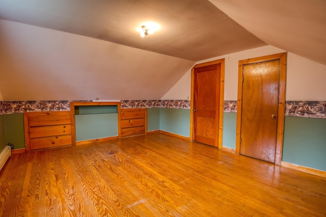 bonus room featuring lofted ceiling, light wood-style flooring, and baseboards