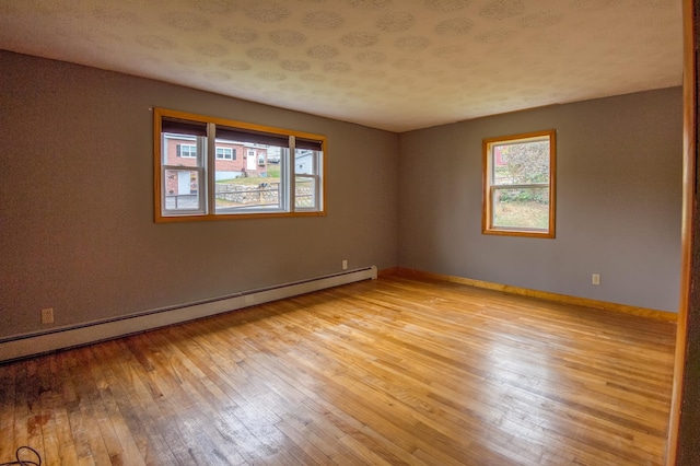 unfurnished room featuring a wealth of natural light, light wood-style flooring, baseboards, and baseboard heating